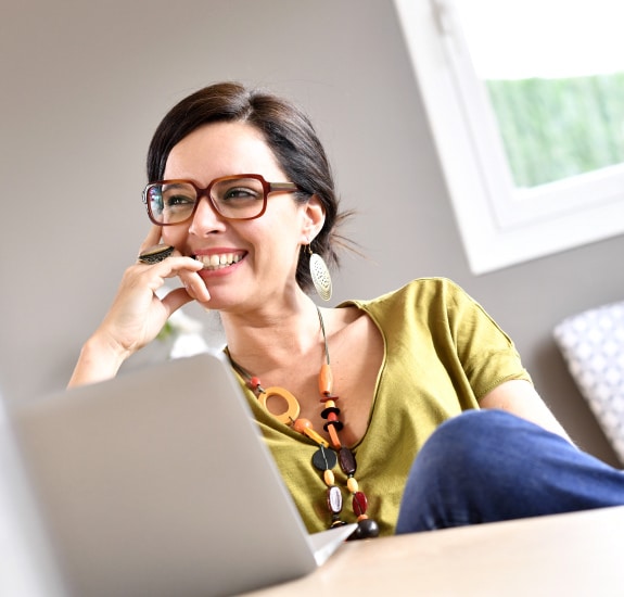 Middle-aged woman smiling while looking up from laptop computer